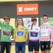 Women in green, yellow, white and polka dot cycling jerseys on podium