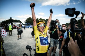 cyclist in yellow with her hands in the air