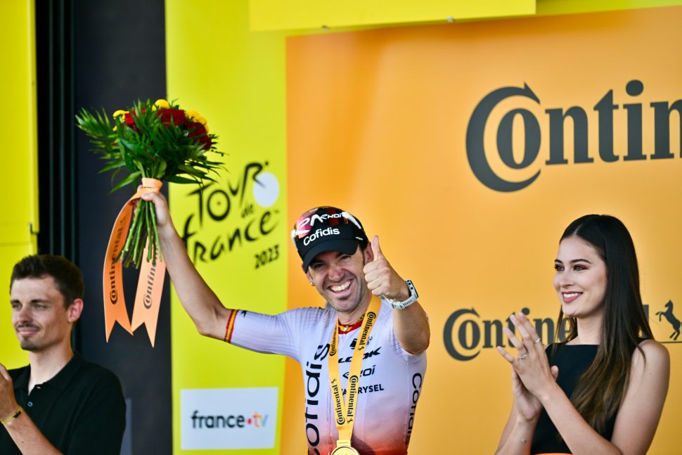 cyclist on podium gives thumbs up to camera
