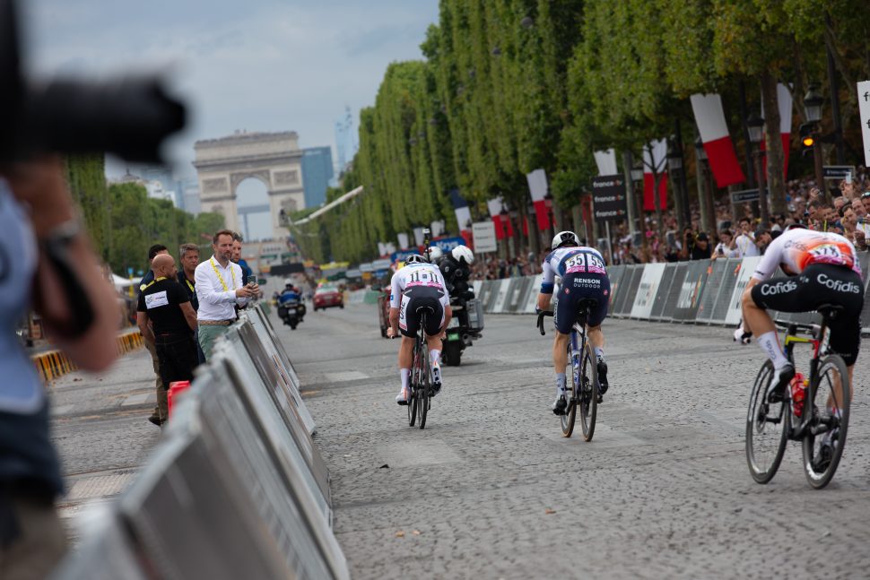 cyclists race towards Arc de Triomphe in Paris