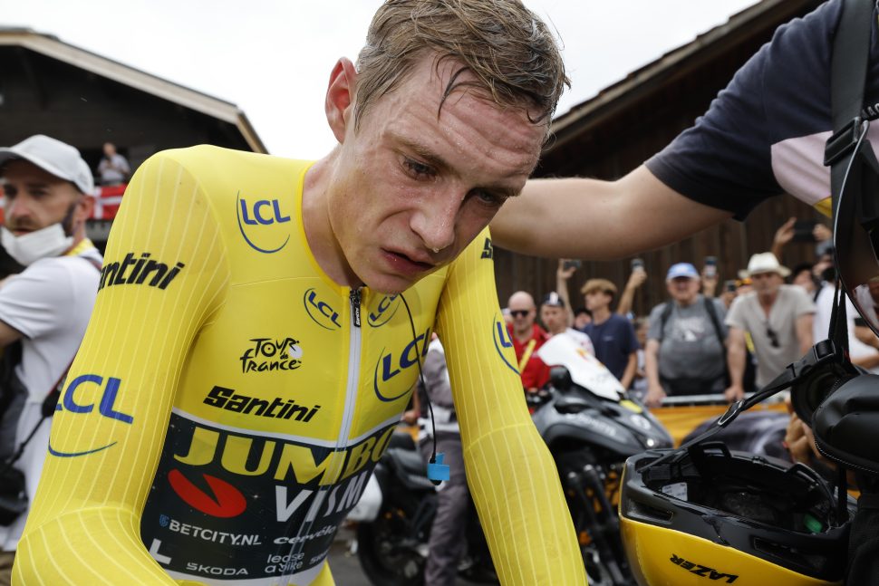 cyclist in yellow with no helmet leans over in exhaustion dripping with sweat