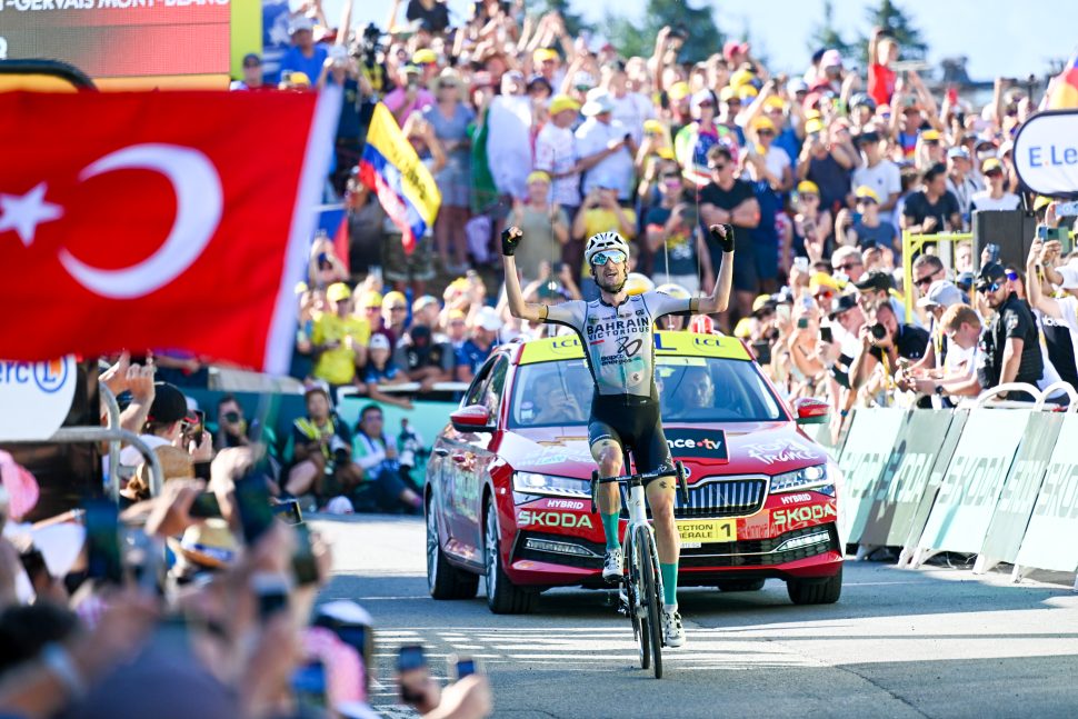 cyclist raises arms in air in front of packed crowd